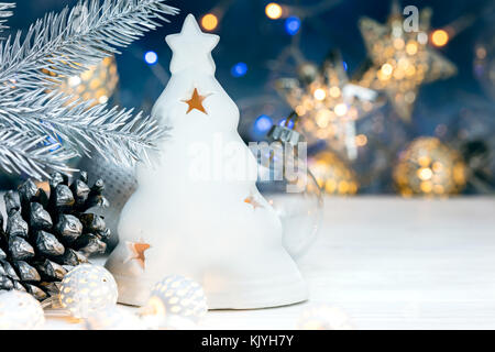 Decorazioni di Natale, abete del ramo con cono sfocate su sfondo blu con una ghirlanda luci Foto Stock