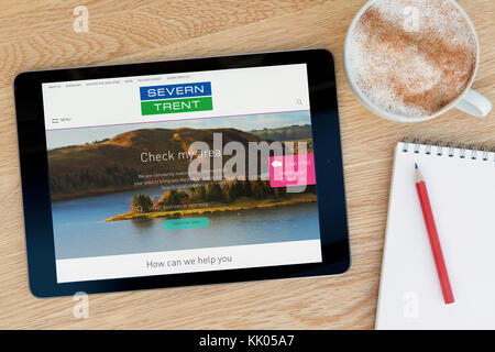 Un uomo guarda la Severn Trent acqua sito sul suo iPad dispositivo tablet, sparato contro un tavolo di legno top sfondo (solo uso editoriale) Foto Stock