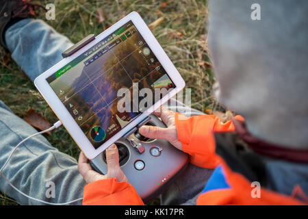 L'uomo operando un drone utilizzando un dispositivo di controllo remoto Foto Stock