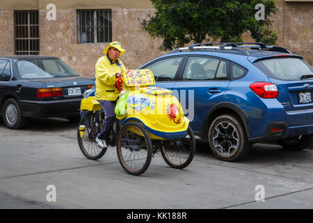 Peruviano scena di strada e lo stile di vita locale: ice-cream venditore consegna uomo su un giallo a tre ruote triciclo in una strada a Miraflores Lima, Perù Foto Stock