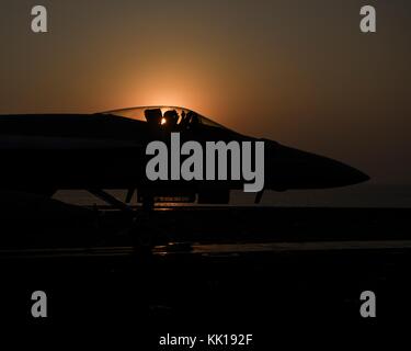 Un U.S. NAVY F/A-18E Super Hornet jet fighter aircraft si prepara a lanciare dal ponte di volo della marina degli Stati Uniti nimitz-class portaerei USS nimitz al tramonto settembre 19, 2017 nel Golfo Arabico. (Foto di mcss emily johnston via planetpix) Foto Stock