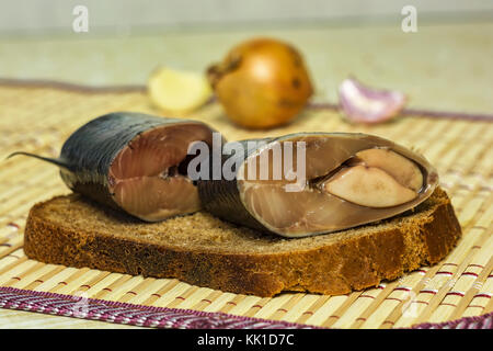 Su una fetta di pane nero sono pezzi di aringhe close-up Foto Stock