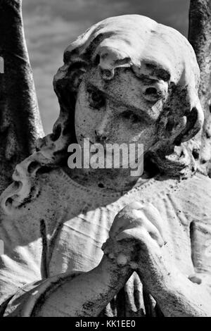 Le mani giunte di un angelo in preghiera tenere un rosario. Foto Stock