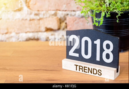 Nuovo anno 2018 tendenze sulla lavagna segno e pianta verde sulla tavola di legno in corrispondenza di un muro di mattoni.business plan per il prossimo anno Foto Stock