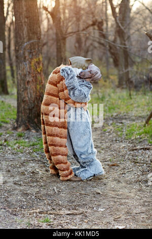 Funny giovane in amore abbracciando indossando il carnevale di cane e di gatto costumi all'aperto nella foresta Foto Stock