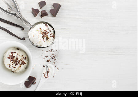 Porzione di gelato alla crema con topping di cioccolato nella piastra bianca sul tavolo di legno, vista dall'alto Foto Stock