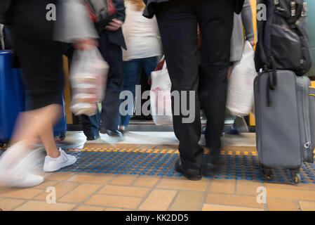 Un basso angolo, leggermente sfocati colpo di persone o pendolari di salire a bordo di un treno in ora di punta a Sydney in Australia Foto Stock