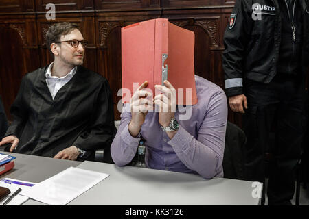 Amburgo, Germania. 29 novembre 2017. L'imputato nasconde il suo volto dietro un fascicolo mentre siede accanto al suo avvocato Oliver Klostermann (L) presso il tribunale del distretto di Altona ad Amburgo, Germania, il 29 novembre 2017. Egli è accusato di aver messo in atto un pericoloso intervento nel trasporto aereo e di pericolosi danni fisici durante le proteste del vertice del G20 di luglio. (ATTENZIONE REDATTORI: I dettagli sui giornali sono pixellati per motivi legali.) Credito: Markus Scholz/dpa/Alamy Live News Foto Stock