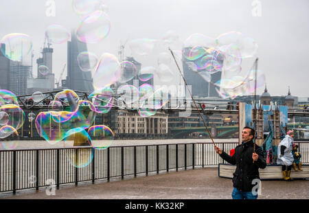 Banca del sud del fiume Tamigi uomo percorso di intrattenimento per bambini e persone con bolle, Londra, Inghilterra, Regno Unito con il Millennium Bridge e pop up Orso Paddington Foto Stock