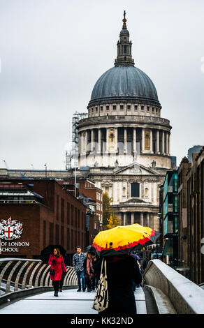 La gente che camminava sul Millennium Bridge sul giorno di pioggia con luminosi ombrelloni alla Cattedrale di St Paul e la City of London School, Thames, Inghilterra, Regno Unito Foto Stock