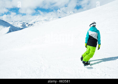 Snowboarder donna su sullo sfondo di un paesaggio innevato di alta montagna Foto Stock