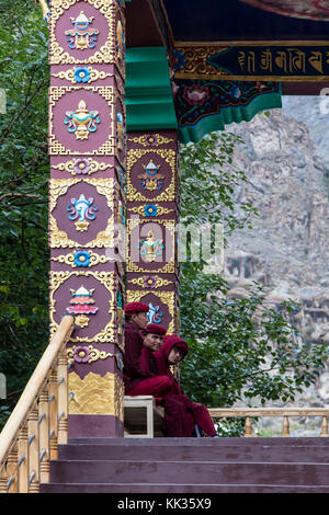 Tre monaci siedono all'ingresso del MONASTERO DI HEMIS - valle di LEH, LADAKH Foto Stock
