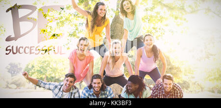 Happy amici nel parco rendendo piramide umana contro essere completata Foto Stock