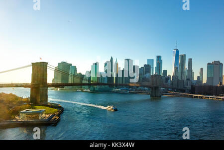 Un East River Ferry passando sotto il ponte di Brooklyn con la parte inferiore della skyline di Manhattan in background Foto Stock