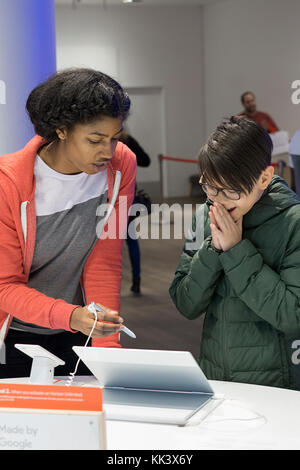 Un addetto allo stand mostra un entusiasta Asian American boy nuova tecnologia dei computer all'interno del Google pop up store sulla Fifth Avenue a Manhattan, New York City Foto Stock