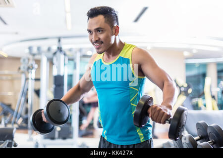 Bel giovane determinato esercizio con manubri in un mod Foto Stock