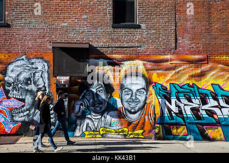 Persone che camminano oltre un muro di graffiti nel quartiere Carroll Gardens di Brooklyn, New York Foto Stock