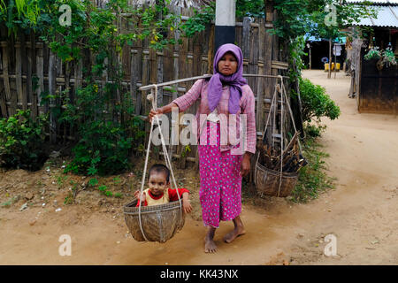 Donna che la porta in legno e un bambino in un villaggio vicino a Bagan, Myanmar Foto Stock