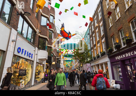 Persone che camminano in Carnaby Street, sotto il Natale a tema di Carnevale le luci di Natale, Londra Foto Stock