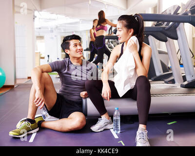 Giovani asiatici l uomo e la donna in chat in palestra mentre prendendo una pausa. Foto Stock