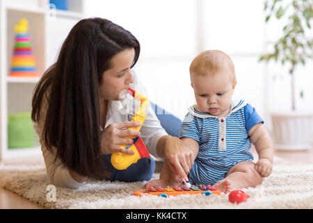 Mamma e Bambino giocare giocattoli musicali a casa Foto Stock