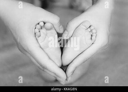 I talloni del neonato nella madre le mani formando un cuore Foto Stock