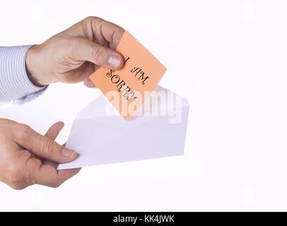 Involucro bianco con carta nota con man mano sullo sfondo bianco. Mi dispiace concetto. Foto Stock