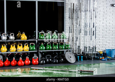 La sala sportiva con pesi, manubri, bar sullo sfondo di un vetro scuro e grigio di un muro di mattoni Foto Stock