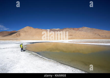 Giovane ragazzo accanto a una fluttuazione di Salt Lake Tso Kar nel paesaggio arido e strati di sale su una limpida giornata autunnale, Ladakh, India Foto Stock