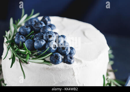 La crema bianca torta con mirtilli freschi decorate di rosmarino fresco. il concetto di inverno panificio. Foto Stock