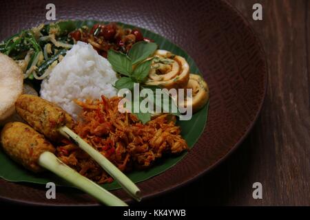 Il Nasi Campur Bali. Popolare il riso Balinesi piatto di riso al vapore con assortimento di piatti laterali, serviti insieme su una piastra. Foto Stock