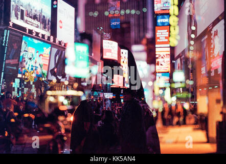 Doppia esposizione della donna che cammina attraverso colorate e luminose times square di new york city Foto Stock