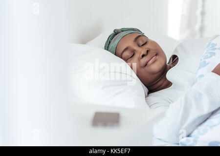 Giovane donna africana indossando un velo dormire nel letto Foto Stock