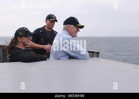 Golfo Arabico (nov. 23, 2017) segretario della Marina Richard V. Spencer, sua moglie Sarah Pauline Spencer e Cmdr. Jeffrey Tamulevich (sinistra), comandante della Arleigh Burke-class guidato-missile destroyer USS tramoggia (DDG 70), la vista della nave in transito il Golfo Arabico dal ponte ala sul giorno del Ringraziamento. La tramoggia è distribuito negli Stati Uniti Quinta Flotta area di operazioni a sostegno della sicurezza marittima operazioni per rassicurare gli alleati e partner e preservare la libertà di navigazione e il libero flusso di commercio nella regione. (U.S. Foto di Marina di Massa lo specialista di comunicazione 2a classe Kri Foto Stock