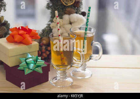 Una festosa vita ancora con due vetri chiaro tea cups, due confezioni regalo, una ghirlanda di pino Foto Stock