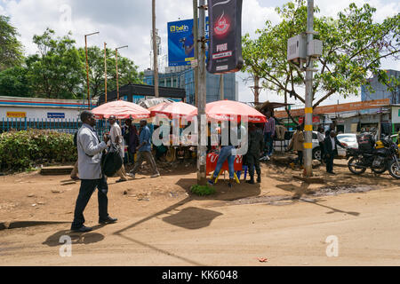 Tipica scena di strada di Nairobi con ombreggiato bancarelle che vendono merci e persone camminando sul marciapiede, Kenya, Africa orientale Foto Stock