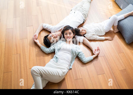 Felice giovane famiglia cinese in appoggio su pavimento in legno Foto Stock