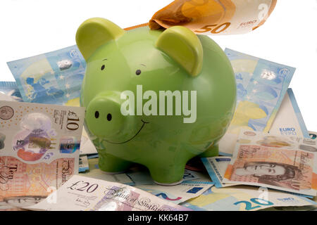 Salvadanaio con Euro e Sterline banconote su sfondo bianco Foto Stock