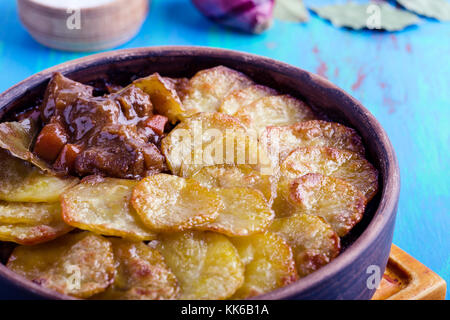 In casa spezzatino di carne e rabboccato con le patate a fette nel recipiente di ceramica, pub inglese tradizionale piatto Foto Stock