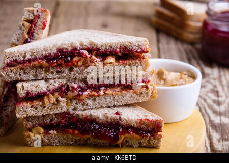 Burro di arachidi e gelatina con sandwich di pane integrale su tavola in legno rustico Foto Stock