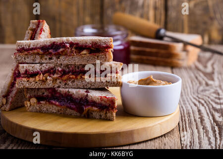 Burro di arachidi e gelatina con sandwich di pane integrale su tavola in legno rustico Foto Stock