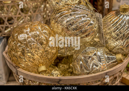 Golden lato vetro soffiato baubles in un cesto di vimini, tipicamente decorazioni natalizie. Foto Stock