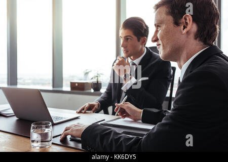 Due proprietari seduti ad un tavolo e guardando lontano. Professionisti aziendali durante una riunione in ufficio. Foto Stock