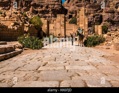 Lastricata Cardo presso il grande tempio, Petra, Giordania, il Medio Oriente e con gli enti locali un uomo su un cavallo che conduce un asino cercando una tariffa turistica Foto Stock