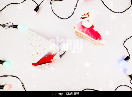 Decorazione di natale con la fetta di torta di doni e fetta di torta sotto la neve con luci per la migliore immagine di sfondo per il messaggio di saluto festivo e banner e blog Foto Stock