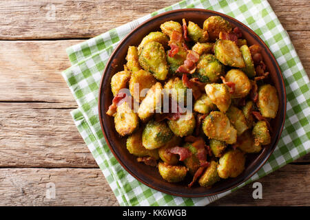 Fritti in panate cavolini di Bruxelles con pancetta close-up su una piastra su un tavolo. parte superiore orizzontale vista da abovel, rustico Foto Stock