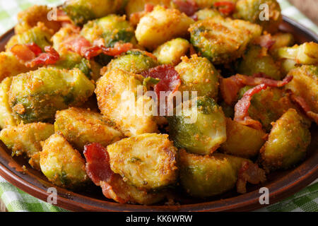 Fried i cavoli di Bruxelles di pangrattato con pancetta macro su una piastra orizzontale. Foto Stock