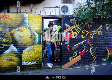 Giovane con un mazzo di fiori di uscire in graffitied vicolo in Shoreditch, Londra, Inghilterra Foto Stock