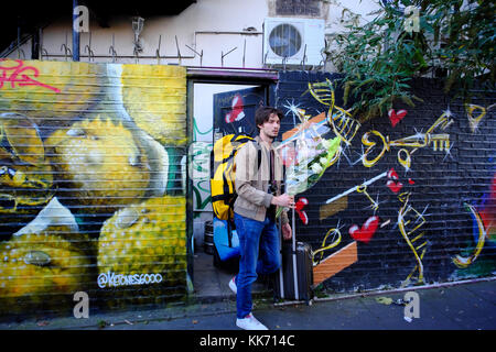 Giovane con un mazzo di fiori di uscire in graffitied vicolo in Shoreditch, Londra, Inghilterra Foto Stock