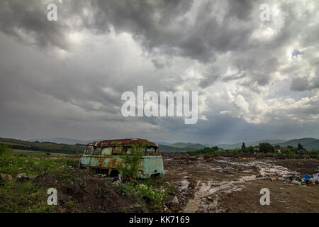 Vecchio autobus abbandonato relitto. colorato paesaggio foto con le nuvole pesanti e il cielo di contrasto Foto Stock